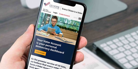 phone in hand with image of person at desk creating us vote foundation voter account